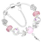 Un bracelet en argent avec des breloques en forme de licorne, de couronne et de cœur. Les breloques sont roses et blanches.