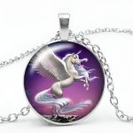 Un pendentif en forme de licorne ailée cabré sur un fond violet. La chaîne est en argent.