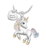 Un collier avec un pendentif en forme de licorne. La licorne est blanche avec une crinière et une queue arc-en-ciel. Elle a un collier avec un pendentif en forme de cœur avec l'inscription "You are magical".