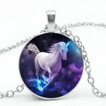 Un pendentif en forme de licorne avec un collier en argent. La licorne est blanche avec une crinière et une queue violettes. Elle est représentée en train de courir dans un ciel étoilé.