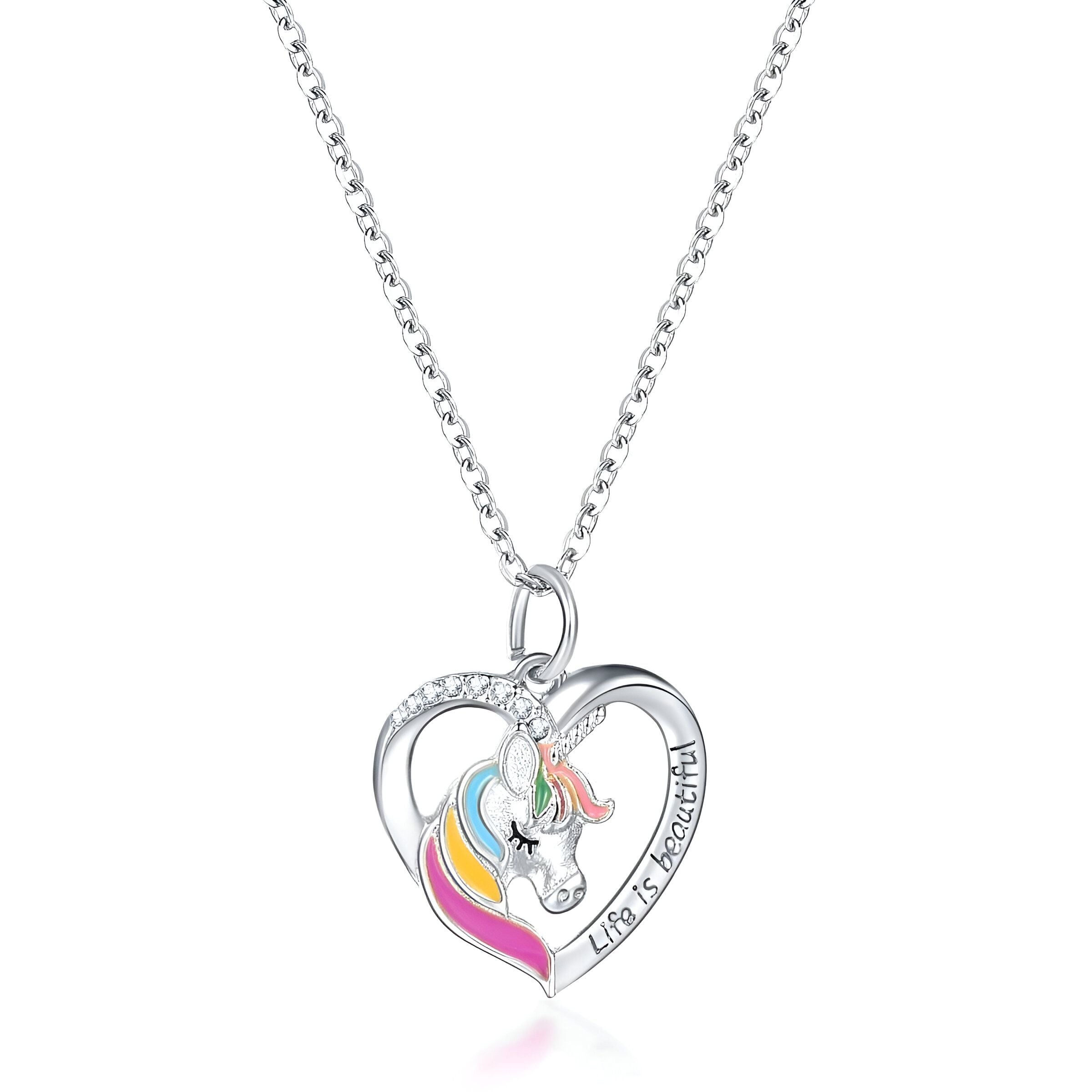 Un collier avec un pendentif en forme de cœur. Le cœur est évidé et l'on peut voir une licorne à l'intérieur. La licorne est blanche avec une crinière et une queue arc-en-ciel. Le pendentif est en argent et serti de zircons. La chaîne est en argent également.