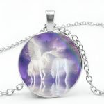 Un pendentif rond en argent avec une image de deux licornes blanches avec des ailes dans un cadre violet.