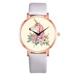 Une montre blanche avec un cadran rond et un bracelet en cuir blanc. Le cadran représente une licorne blanche avec une crinière et une queue roses. La licorne est entourée de fleurs roses, jaunes et bleues.