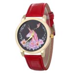 Une montre licorne avec un bracelet en cuir rouge. Le cadran de la montre est noir avec une image de licorne et de fleurs.