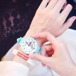 Une personne porte une montre Candycat bleue avec un cadran blanc et un bracelet en silicone. Le cadran de la montre est décoré d'un motif de licorne.
