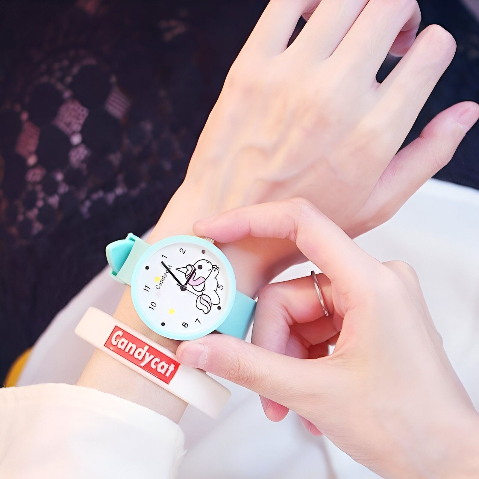 Une personne porte une montre Candycat bleue avec un cadran blanc et un bracelet en silicone. Le cadran de la montre est décoré d'un motif de licorne.