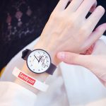 Une jeune fille porte une montre blanche avec un lapin imprimé sur le cadran. Le bracelet de la montre est noir.