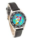 Une montre analogique à quartz avec un bracelet en cuir noir. Le cadran de la montre est bleu avec une image de licorne.